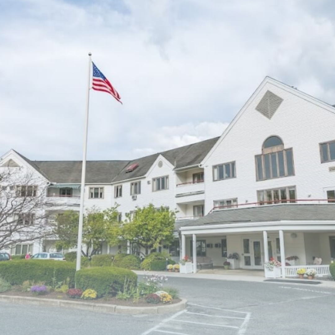 The outside of a careone location. A white building with an American Flag flying in the foreground.