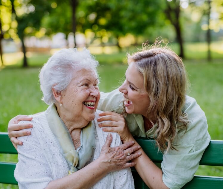 A caregiver and her loved one outside of the assisted living facility