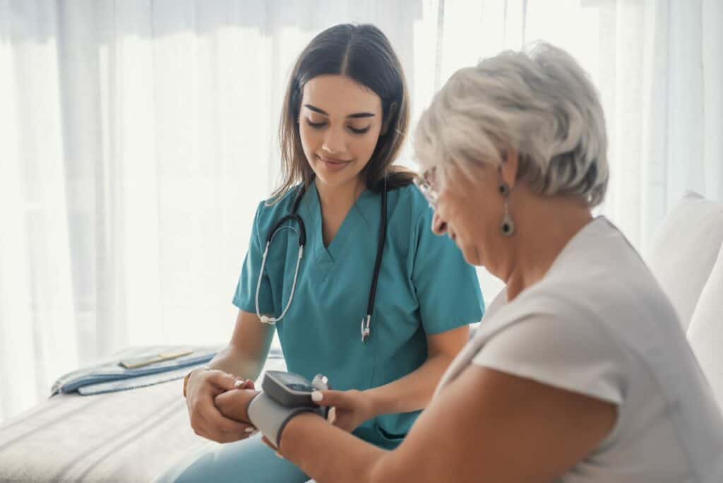 Female caregiver taking blood pressure of older woman