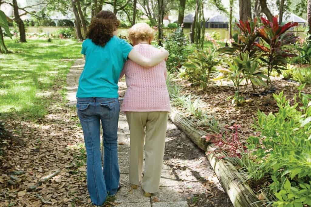 A caregiver and their loved one take a walk on the grounds on an assisted living facility