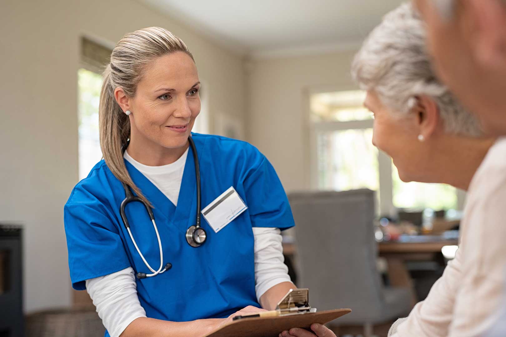 Female caregiver talking with older woman, healthcare