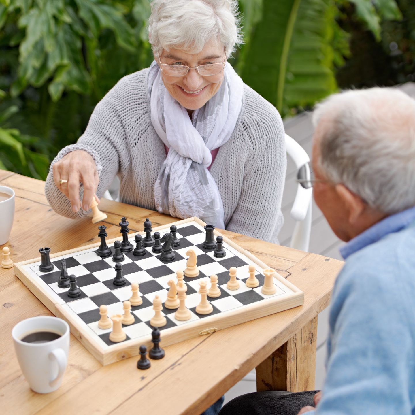 Female and male residents engage in a game of chess outdoors